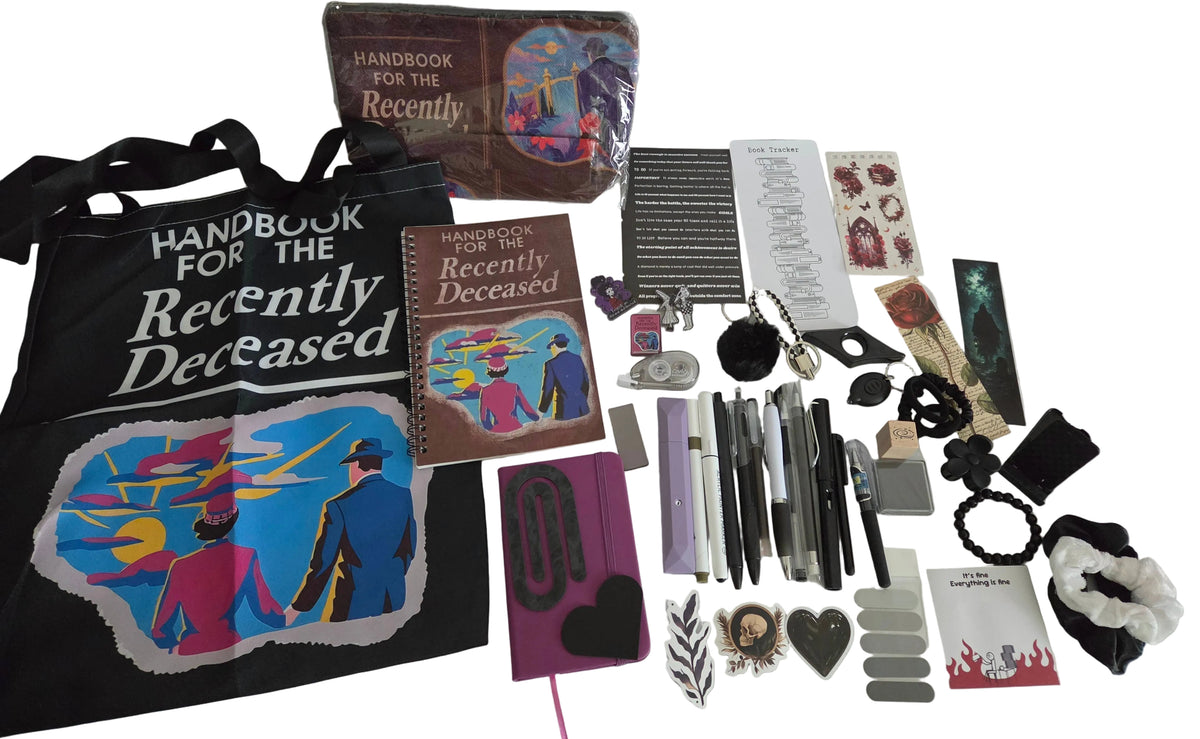 A flat lay of merchandise featuring a black tote bag and a brown notebook with 'Handbook for the Recently Deceased' cover art, alongside matching stationery, stickers, pens, and other accessories 