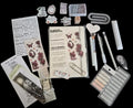 A flat-lay arrangement of various stationery and scrapbooking supplies including a notepad, stickers, paperclips, pens, a heart-shaped tool, a palette, and other accessories