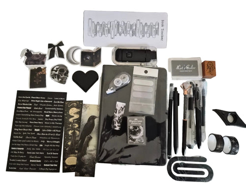 A flat-lay display of a gothic-themed stationery  Bundle includes a black book light, a white sheet of black letter stickers, a black heart-shaped corner page holder, pens, washi tape, a rubber ink stamp, ink pad and various other gothic-themed accessories